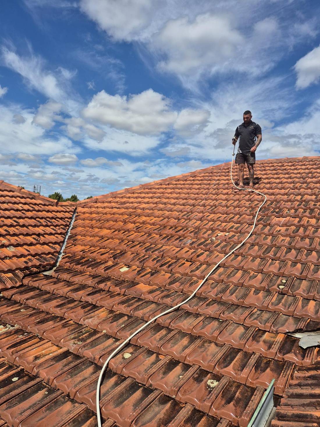 Working across a terracotta tile roof on a clear day
