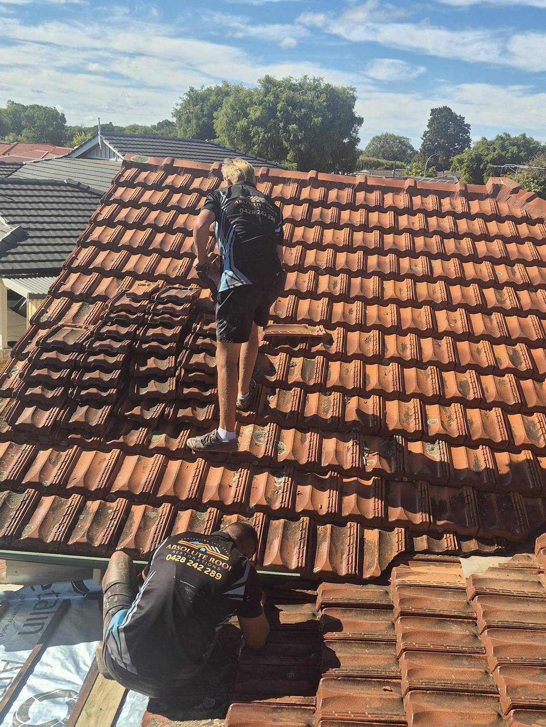 Two of the crew rebedding ridge caps on a terracotta roof