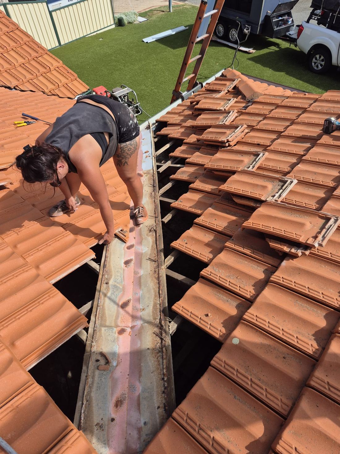 Lifting the tiles back to replace a valley iron on a terracotta roof