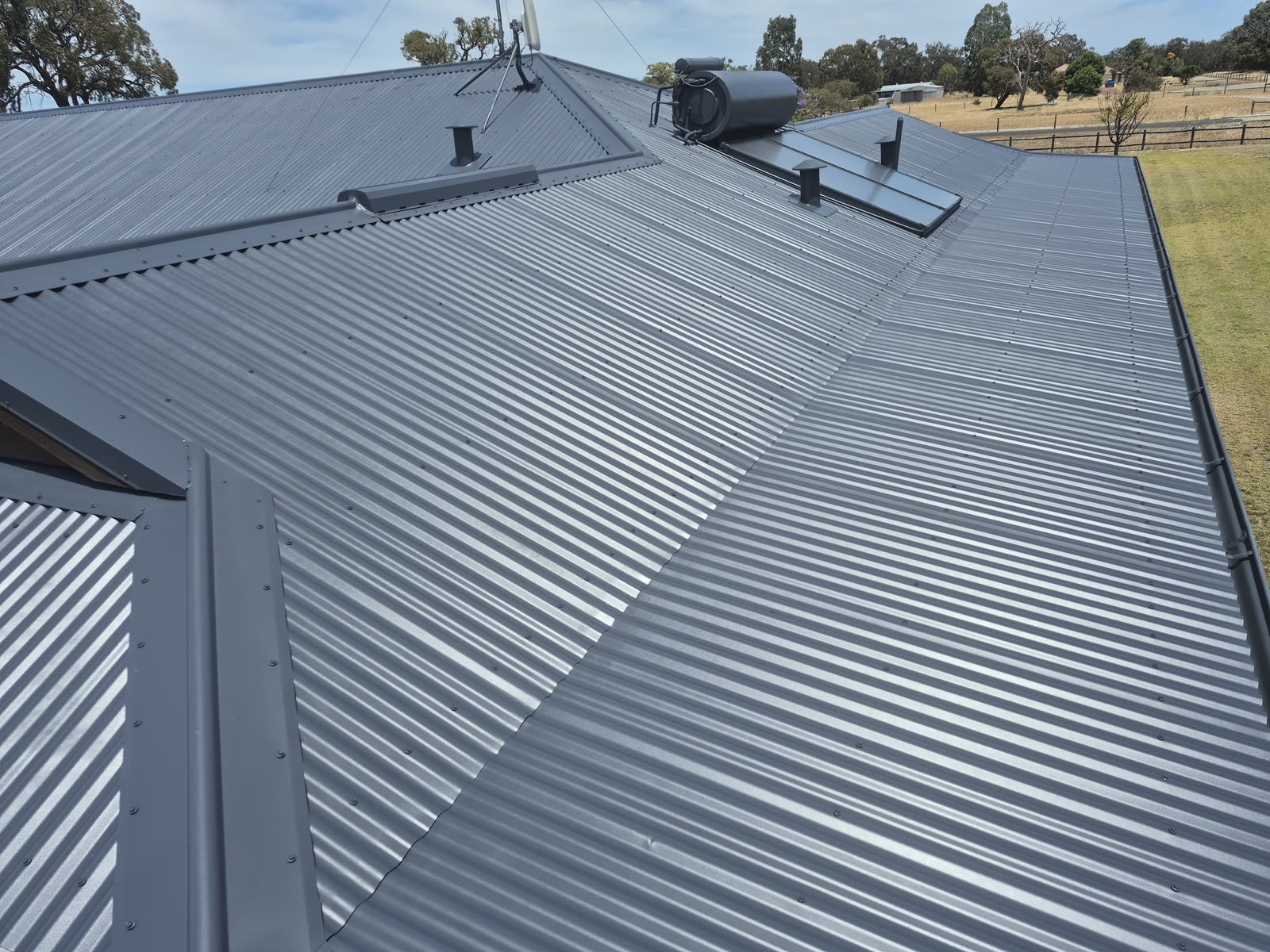 After: the same metal roof cleaned and recoated, an even finish across every sheet
