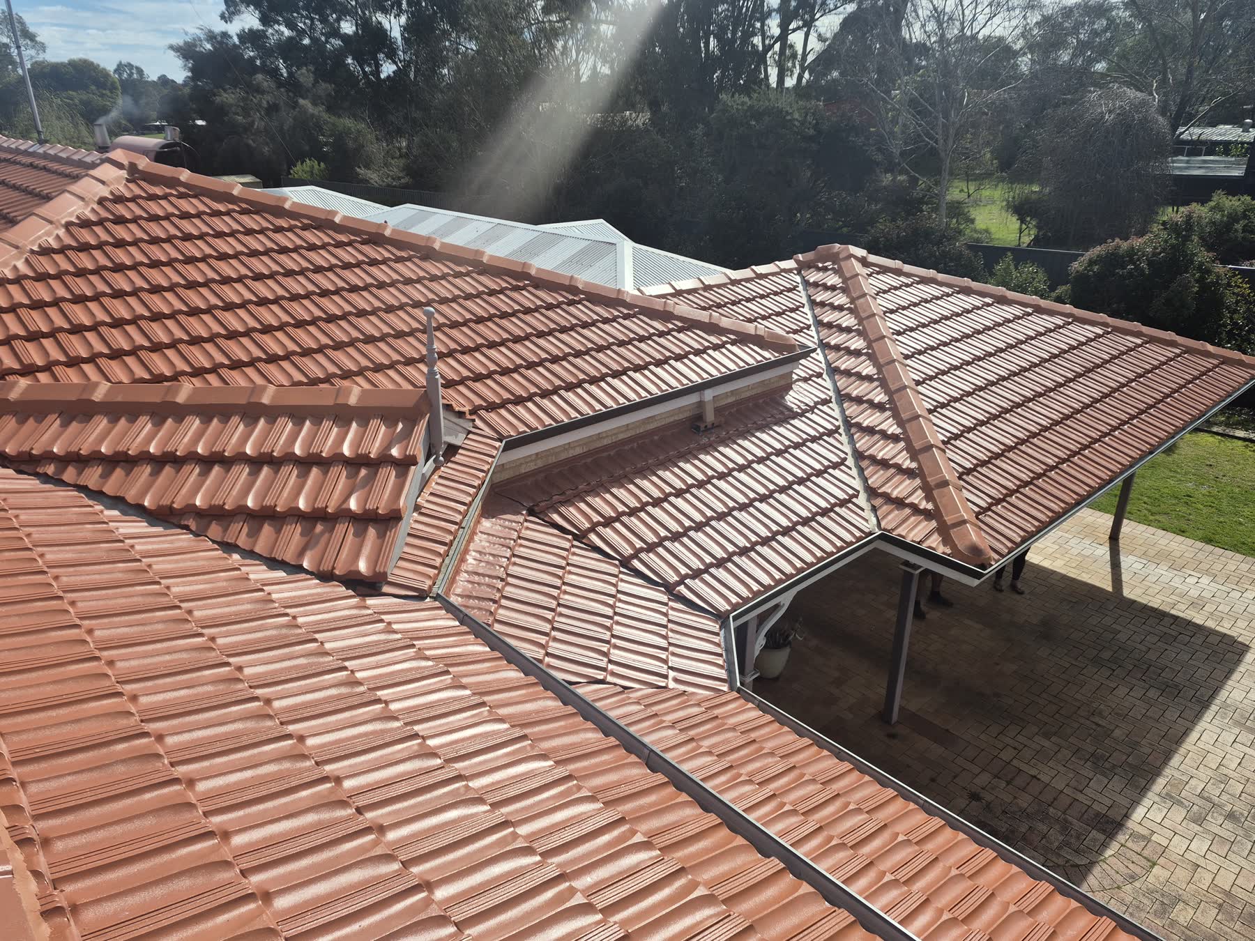 A terracotta tile roof after a full restoration, cleaned and recoated to an even finish