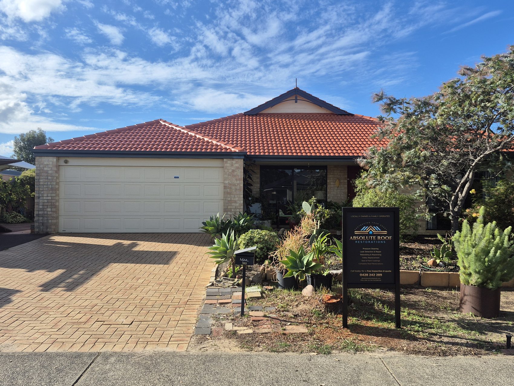 A finished terracotta roof restoration with the Absolute Roof sign out front